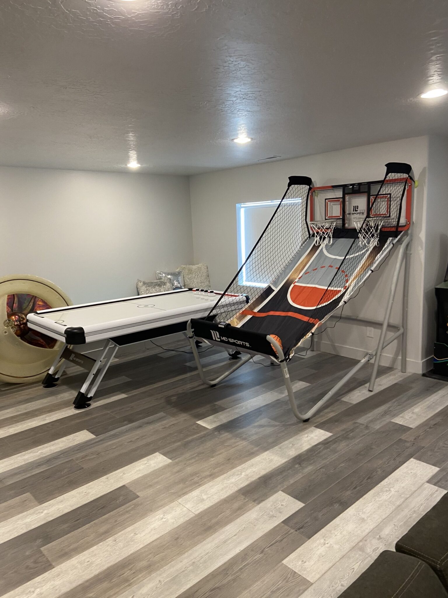 A game room with a pool table, basketball hoop, and a couch. Utah Basement Finishers Man Cave