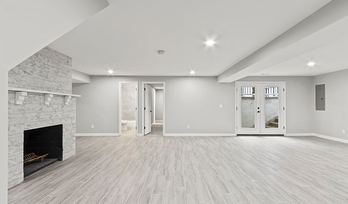Minimalist white room with fireplace and hardwood floors, ideal for basement renovation