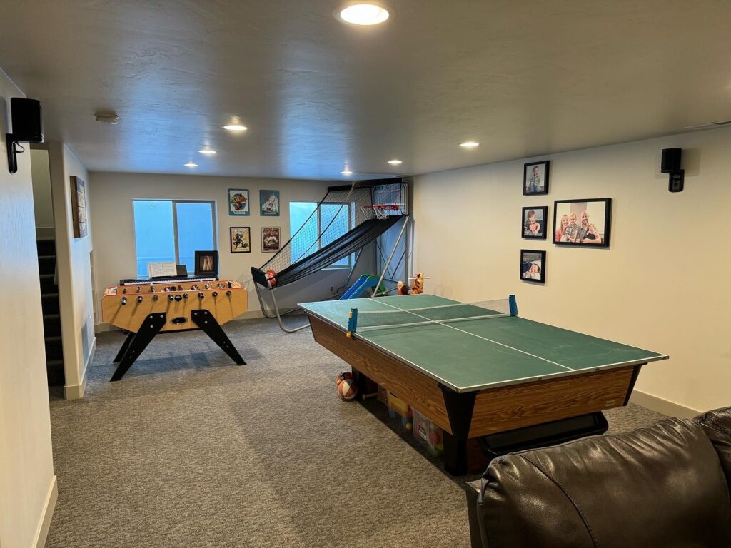 A cozy basement game room featuring a ping pong table and a comfortable couch, perfect for entertainment and relaxation.