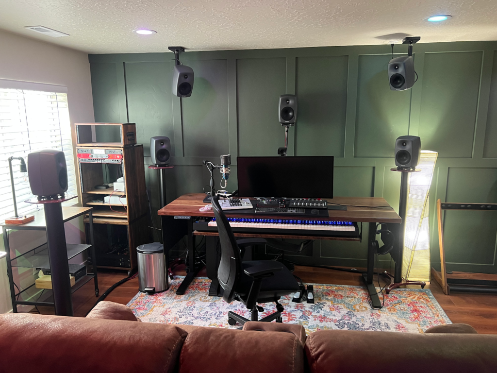 A small basement studio showcasing a desk, speakers, and a couch, ideal for work and leisure in a remodeled space.