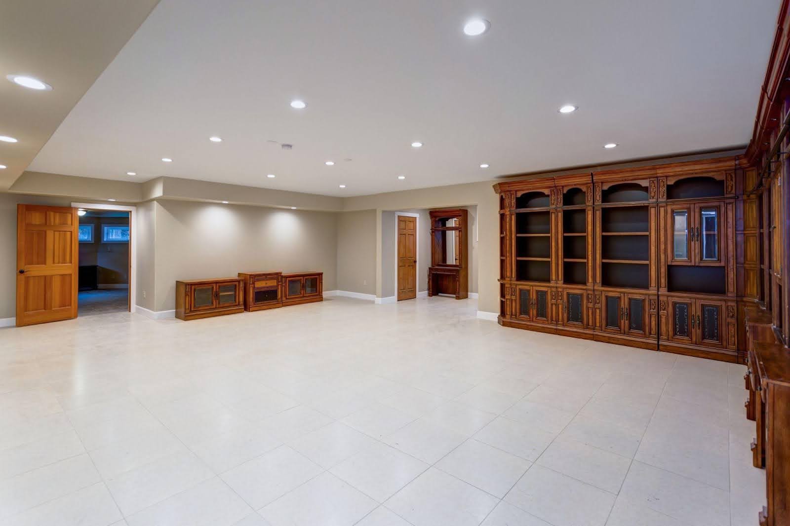 A spacious room featuring white tile floors and wooden cabinets creating a bright and modern atmosphere