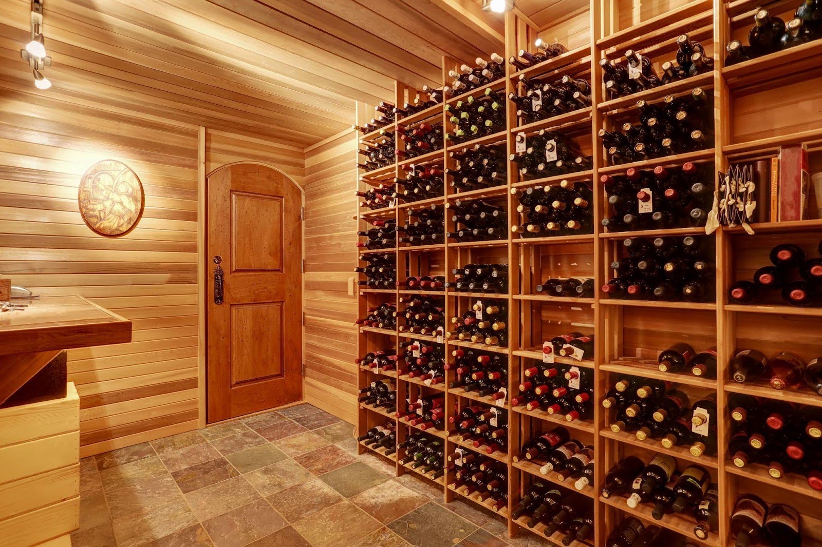 A wine cellar featuring wooden walls and shelves filled with various bottles of wine