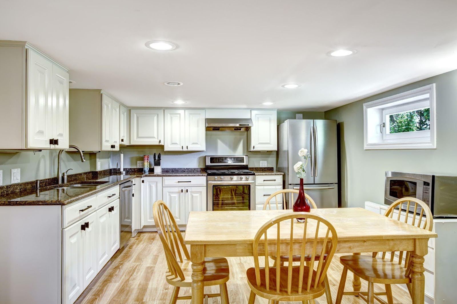 A bright kitchen scene with a table and chairs set for dining, complemented by cabinets and kitchen appliances