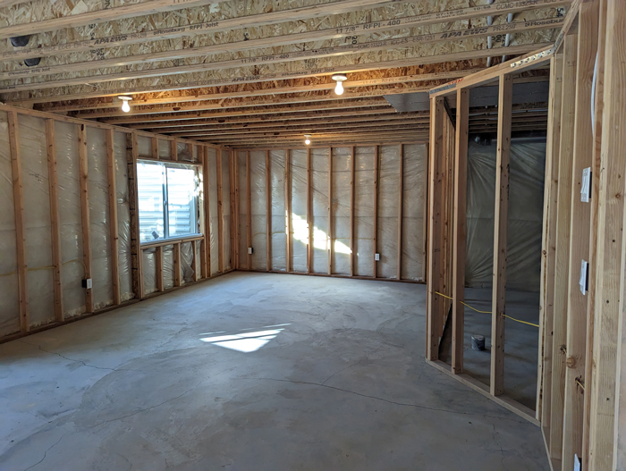 A room featuring unfinished walls and a bare concrete floor indicating a construction or renovation phase